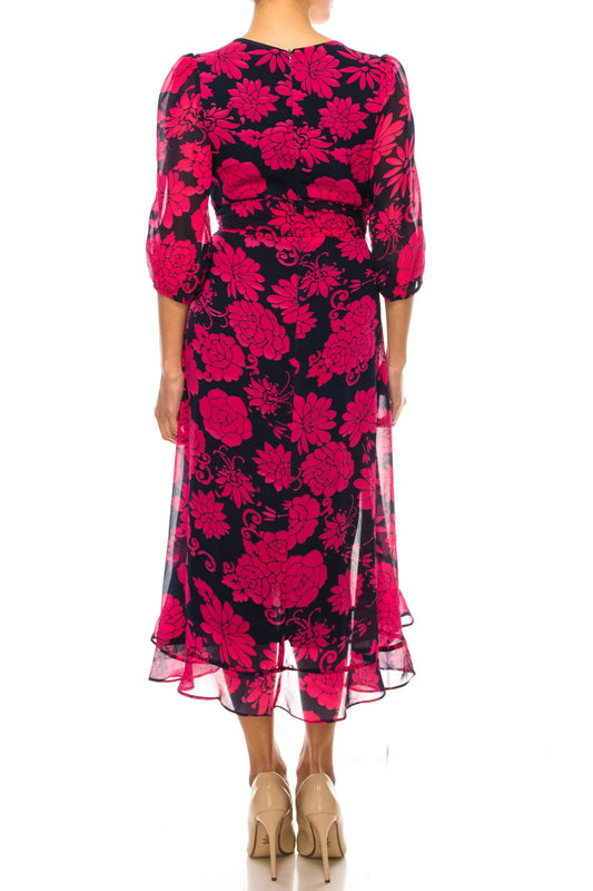Rear view of a woman wearing a navy blue and pink floral print midi dress and beige heels.