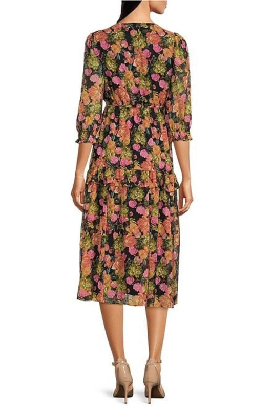 Back view of a woman wearing a black midi dress with a colorful floral print and beige heels.