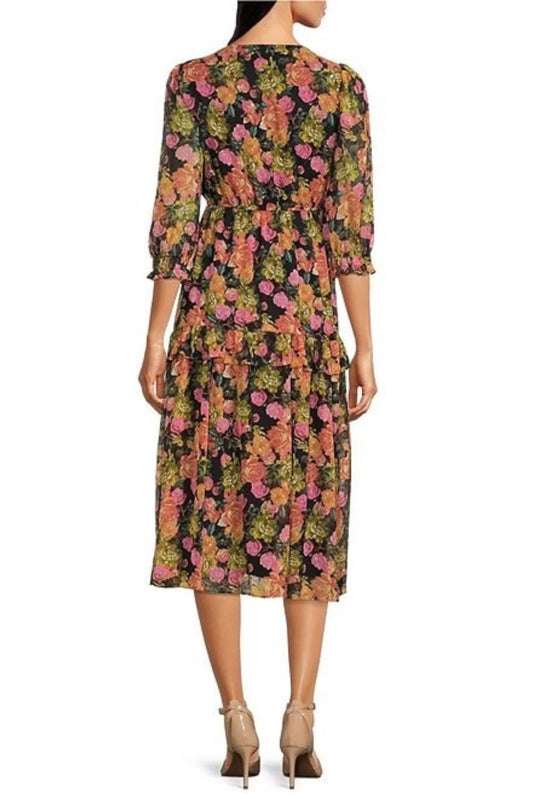 Back view of a woman wearing a black midi dress with a colorful floral print and beige heels.