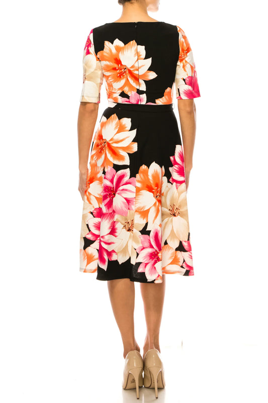 Rear view of a woman wearing a black floral print sheath dress and beige pumps.