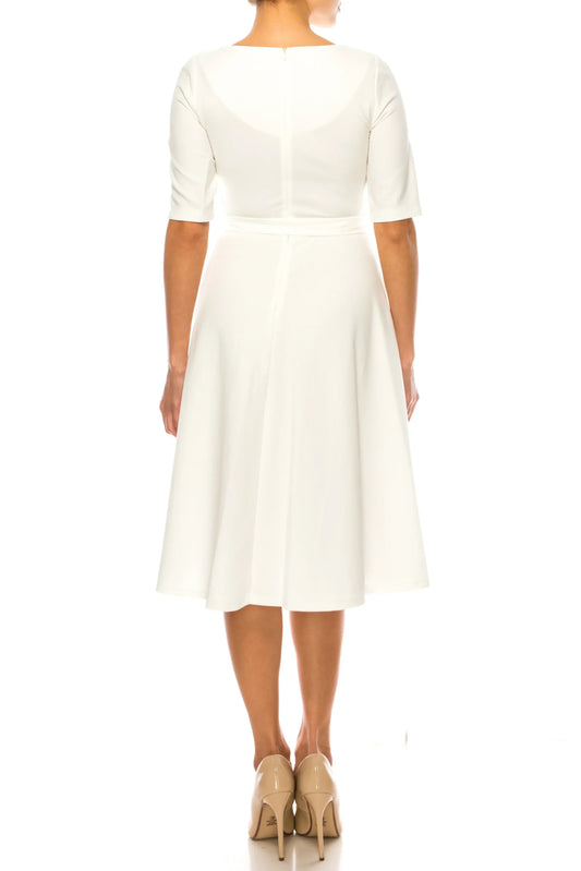 Rear view of a woman wearing an elegant white A-line midi dress and beige heels.