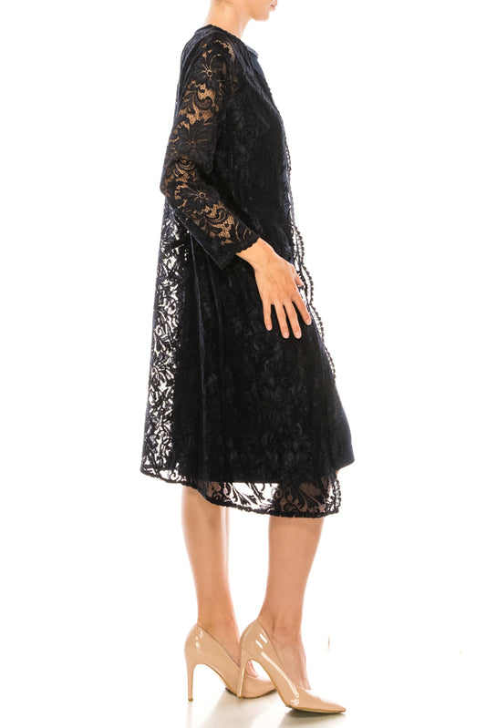 Woman wearing a black floral lace midi dress and nude pointed-toe pumps.