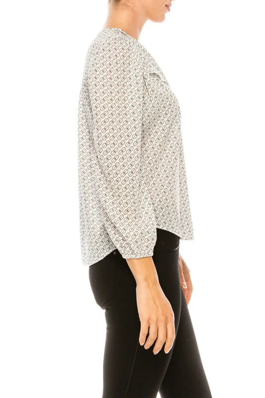 Woman in a white and black geometric print long-sleeve blouse and black pants.
