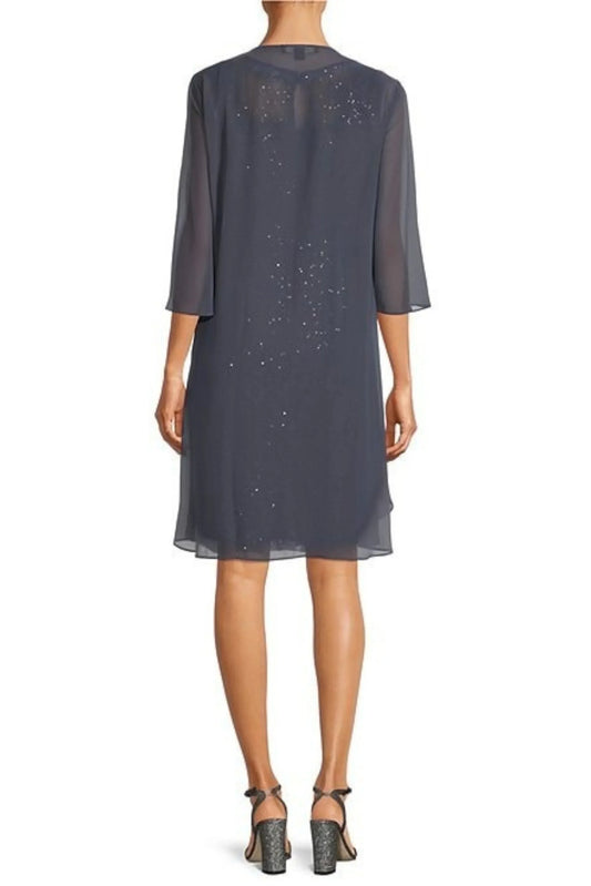 Back view of a woman wearing a charcoal grey sheer midi dress with silver sequin embellishments.