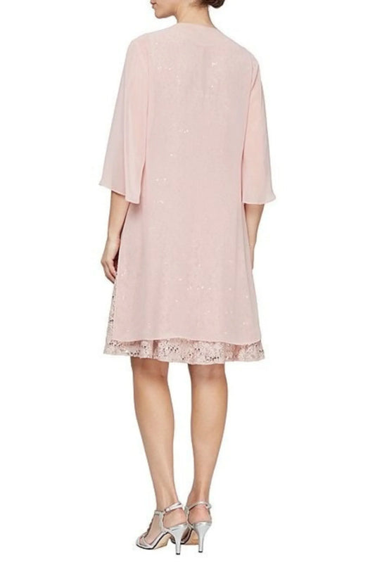 Back view of a woman wearing a light pink knee-length dress with lace trim and silver heels