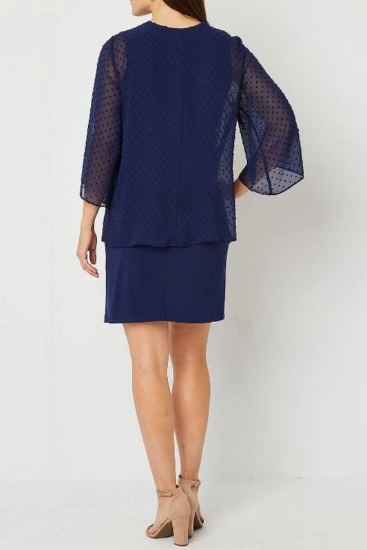 Back view of a woman wearing a navy blue Swiss dot blouse and matching skirt.