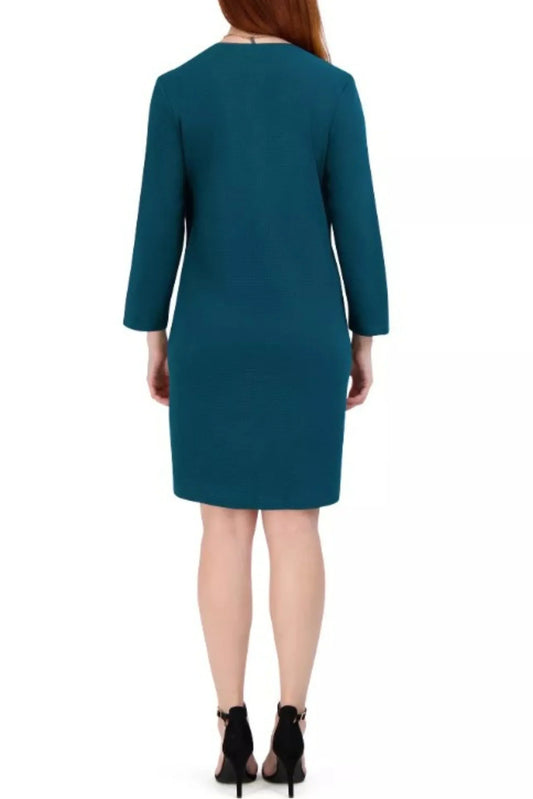 Rear view of a woman wearing a teal long-sleeve sheath dress and black heels