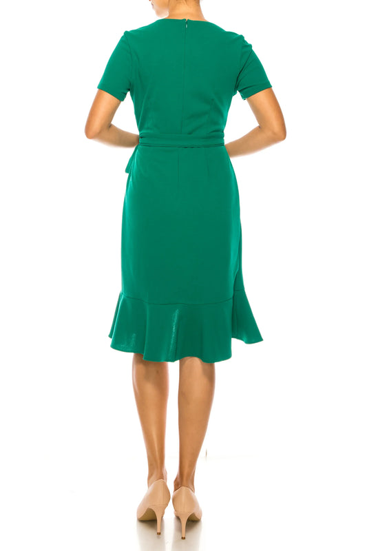 Back view of a woman wearing an elegant green short-sleeve midi dress with a ruffled hem.