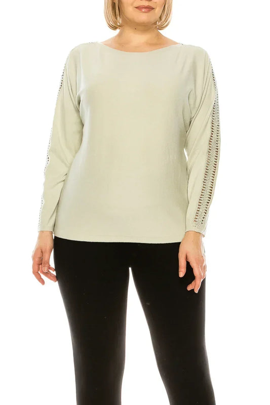 Woman wearing a light sage green long sleeve top with crochet sleeve detailing and black pants