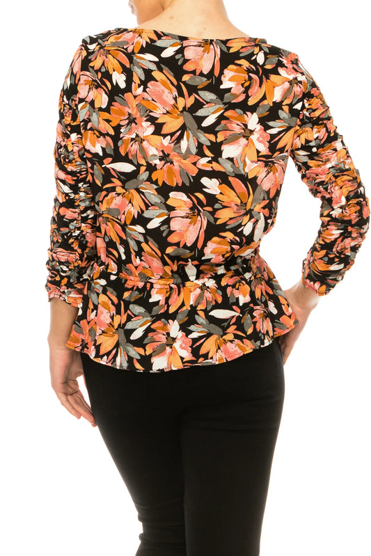 Back view of a woman wearing a floral print peplum top and black pants.