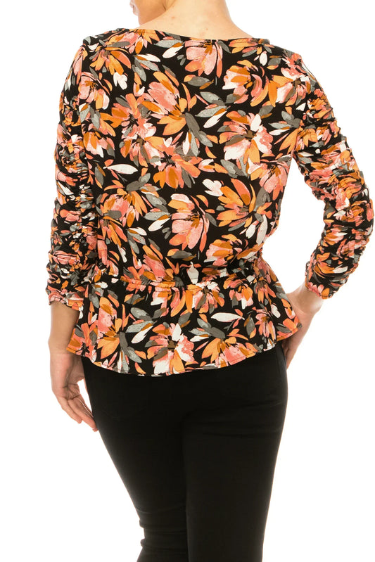 Back view of a woman wearing a floral print peplum top and black pants.