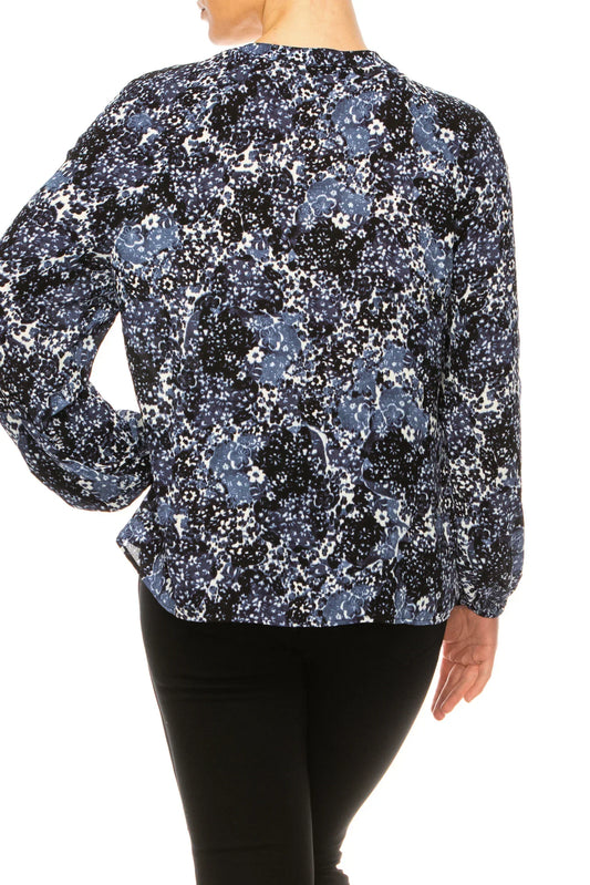 Back view of a woman wearing a navy and white abstract floral print blouse and black pants.