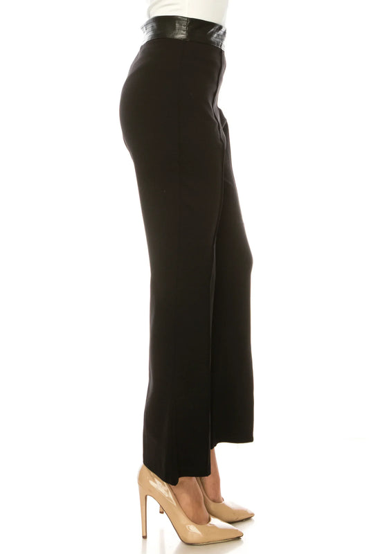 Side view of a woman wearing black wide-leg trousers with a black leather waistband and beige pumps.