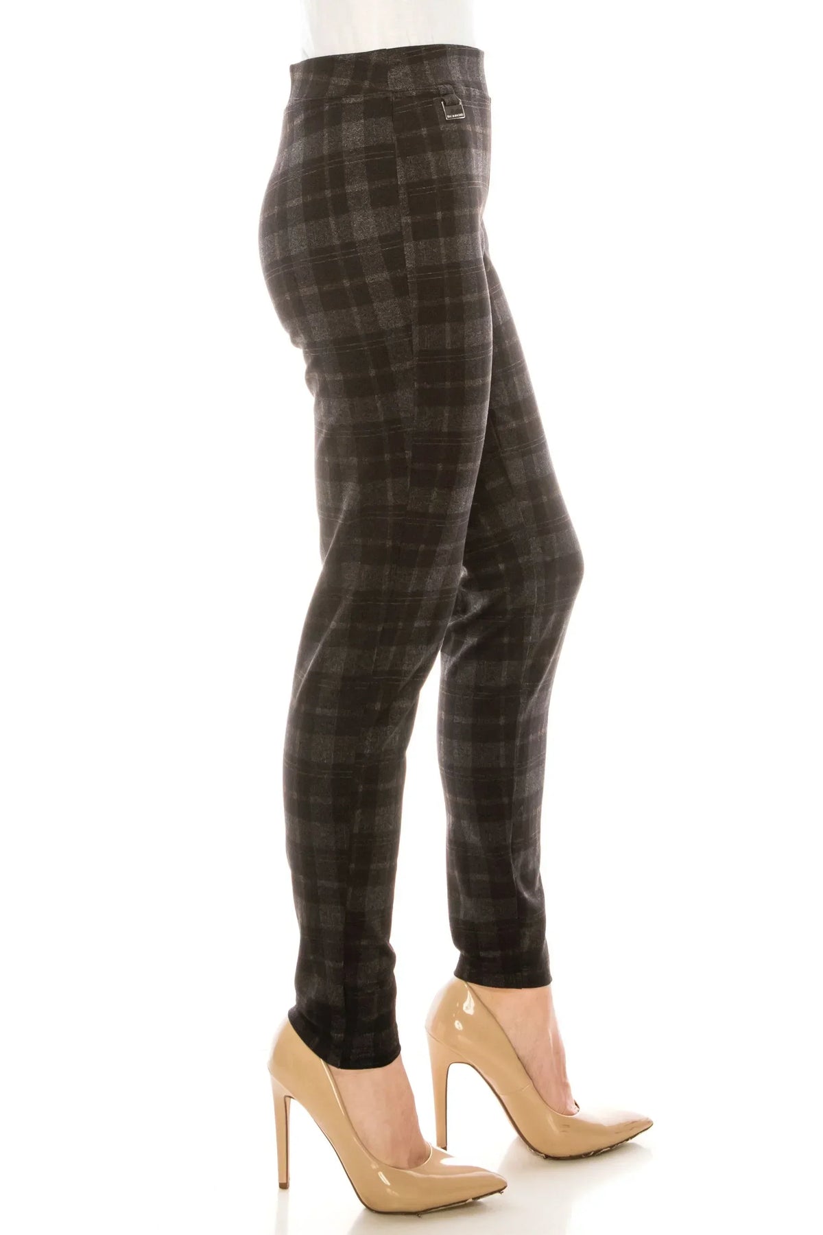 Woman wearing grey and black plaid slim-fit trousers and beige pointed-toe heels.