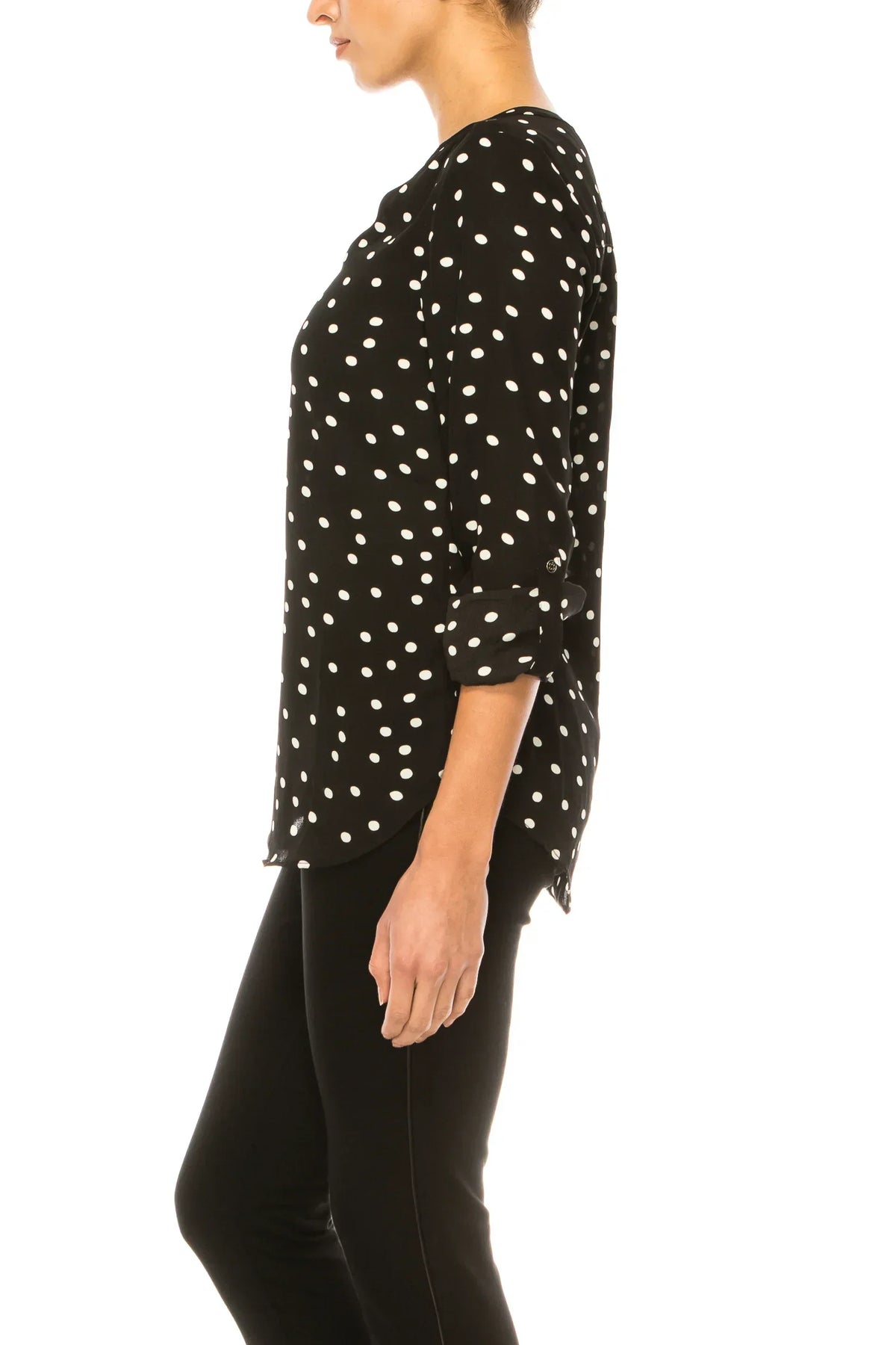 Side view of a woman wearing a black and white polka dot blouse and black trousers.