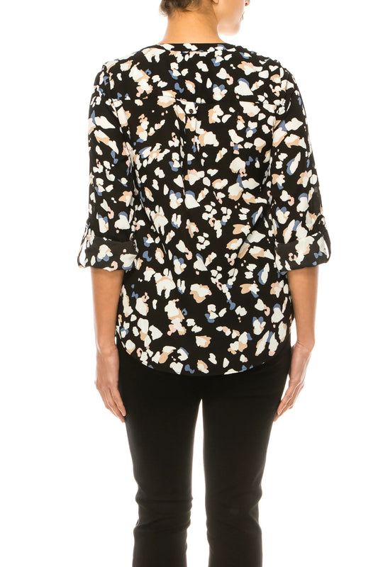 Back view of a woman wearing a black abstract print blouse and black trousers.