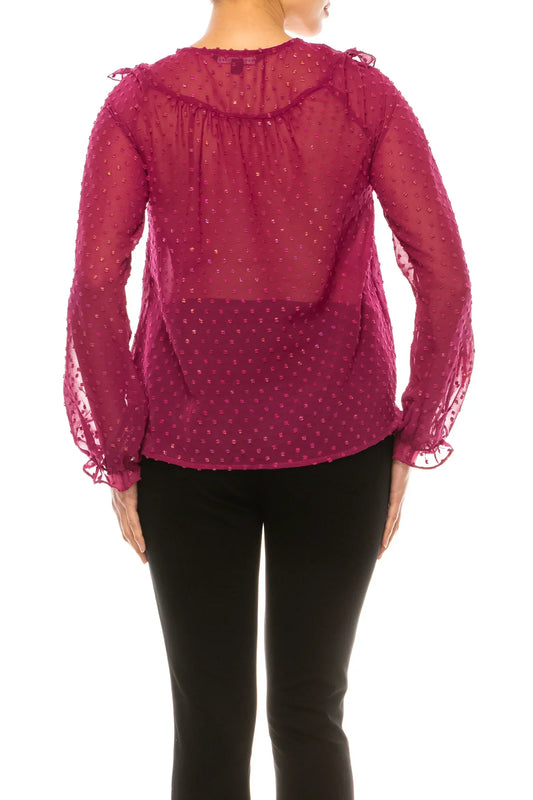 Back view of a woman wearing a magenta sheer polka dot blouse and black trousers.